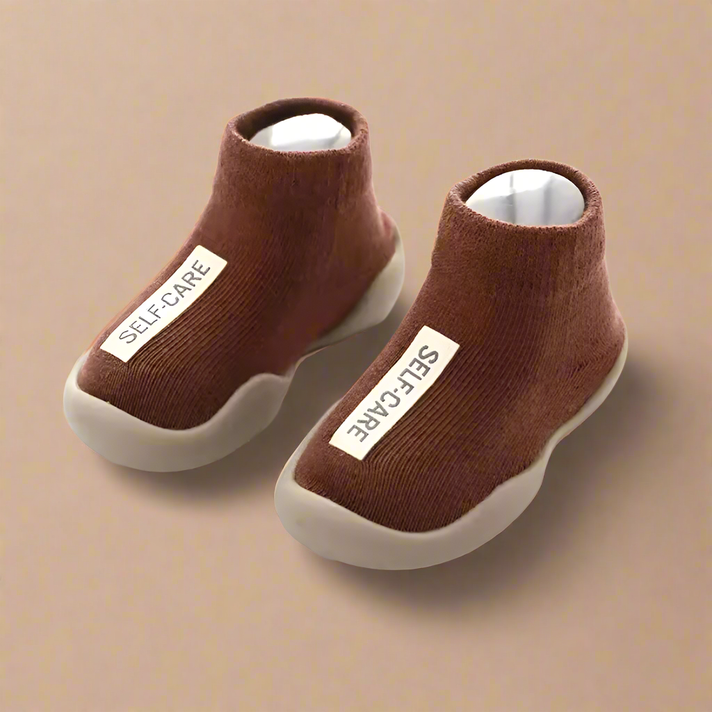 Pair of brown ankle boots with 'SELF-CARE' label on a white background