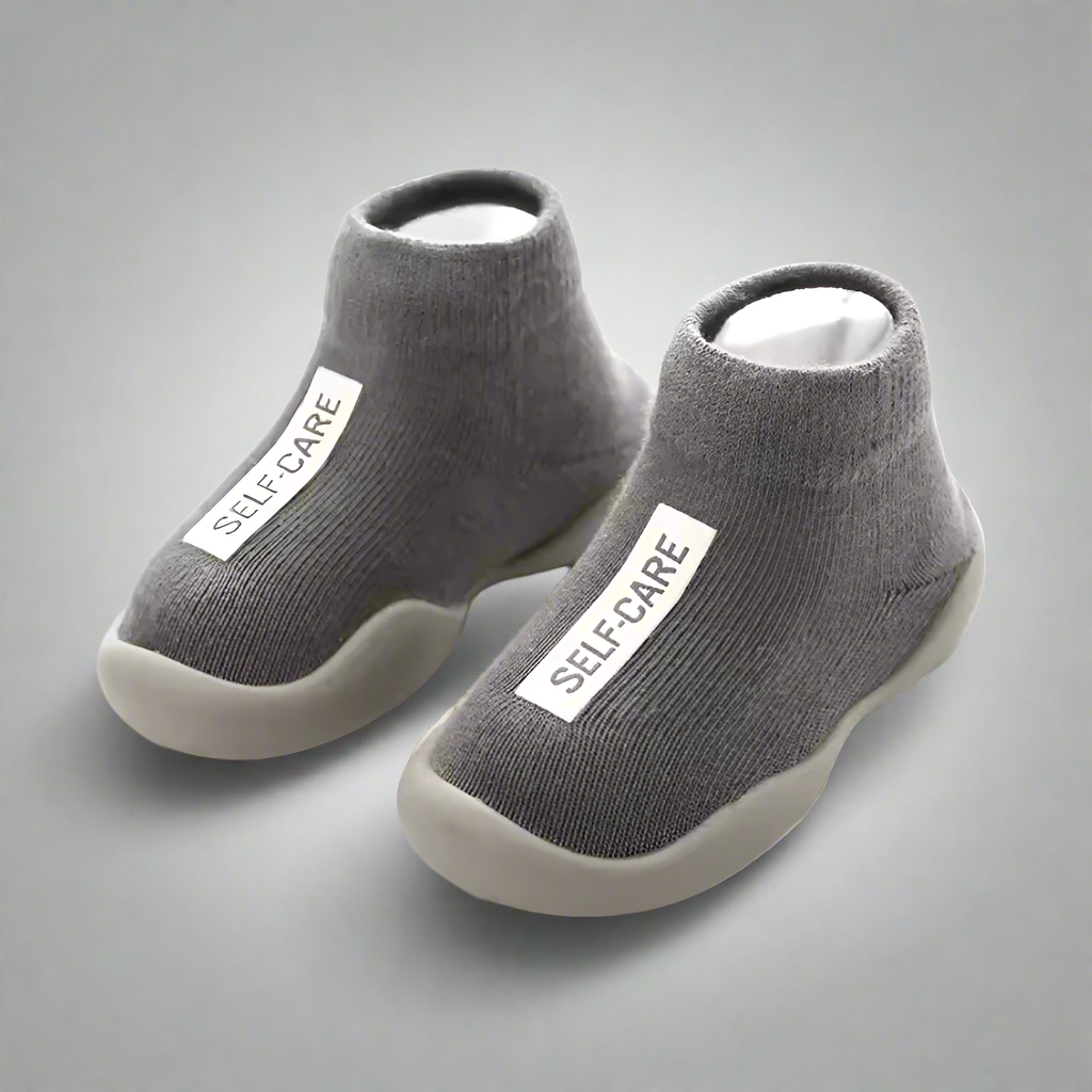 Gray socks with white sole and 'SELF-CARE' label on a white background