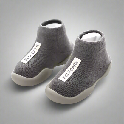 Gray socks with white sole and 'SELF-CARE' label on a white background