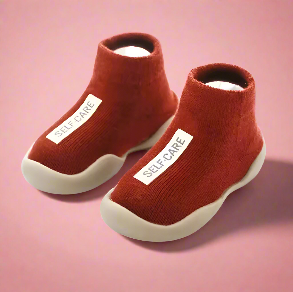 Red slip-on shoes with 'SELF CARE' label on a pink background