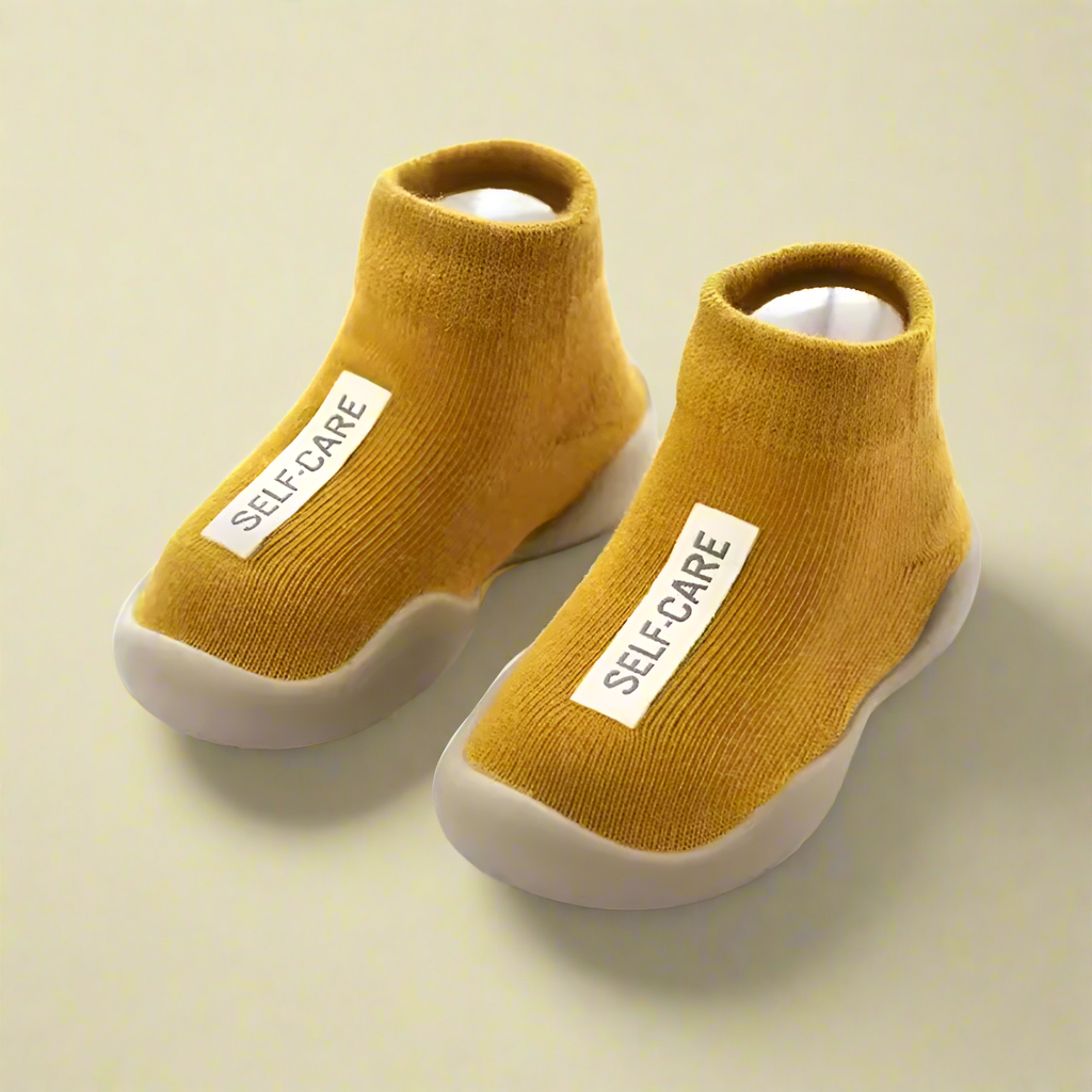Pair of mustard yellow socks with 'SELF CARE' label on a white background